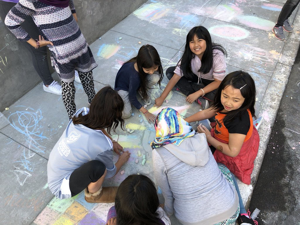 Group of kids chalk drawing on sidewalk