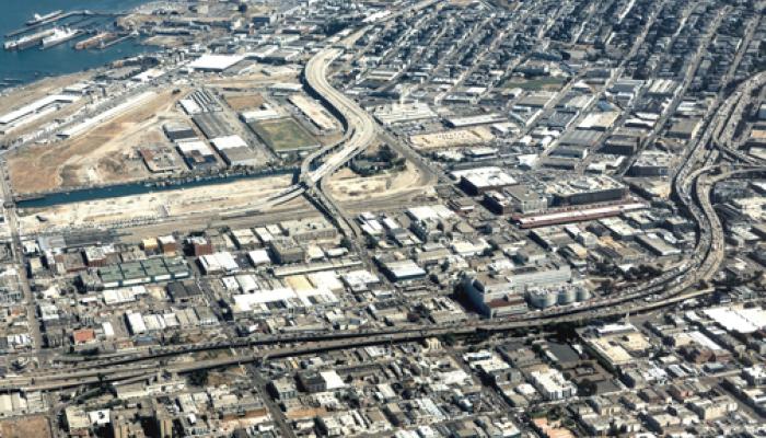 An aerial view of San Francisco's Eastern Neighborhoods, circa 2005, showing a dense mix of industrial and residential blocks, highway interchanges, and the shoreline along the bay.