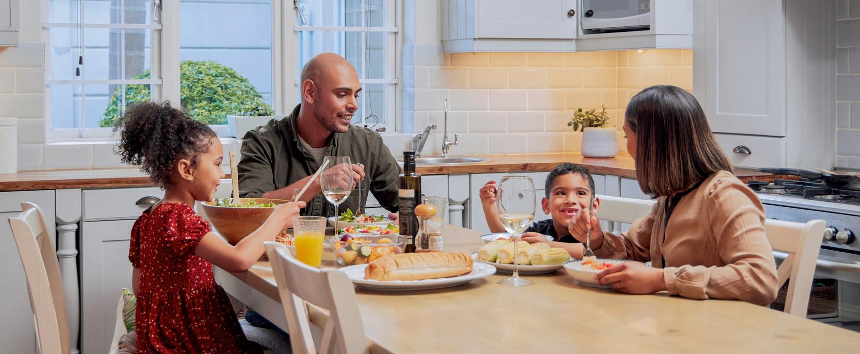 Happy young family sitting at dinner table in kitchen.