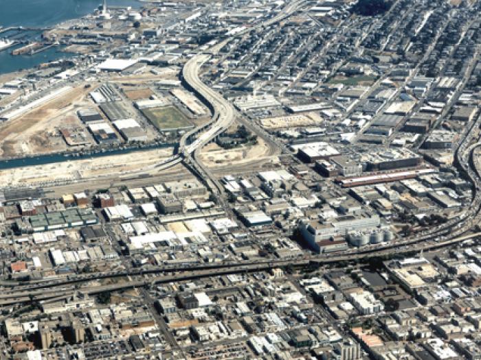 An aerial view of San Francisco's Eastern Neighborhoods, circa 2005, showing a dense mix of industrial and residential blocks, highway interchanges, and the shoreline along the bay.