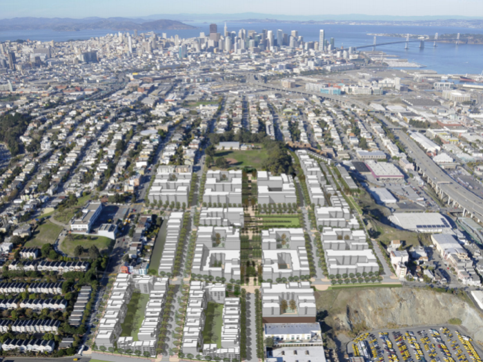An aerial rendering of a proposed high-density urban development in San Francisco, featuring a grid of multi-story white building blocks. The development is situated along a waterfront with several long piers extending into the bay. In the distance, the San Francisco-Oakland Bay Bridge and the downtown skyline are visible under a clear sky.