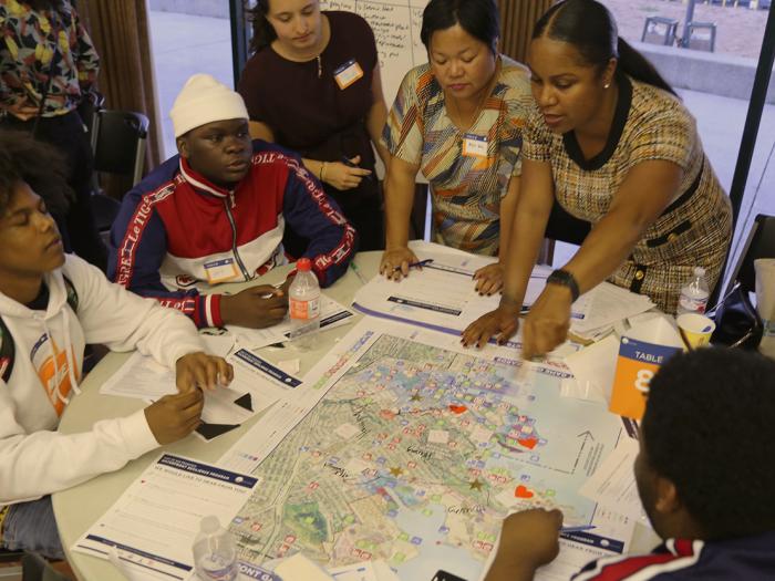 Small group of people sitting and standing around a table pointing at a map. Photo by SF Planning.